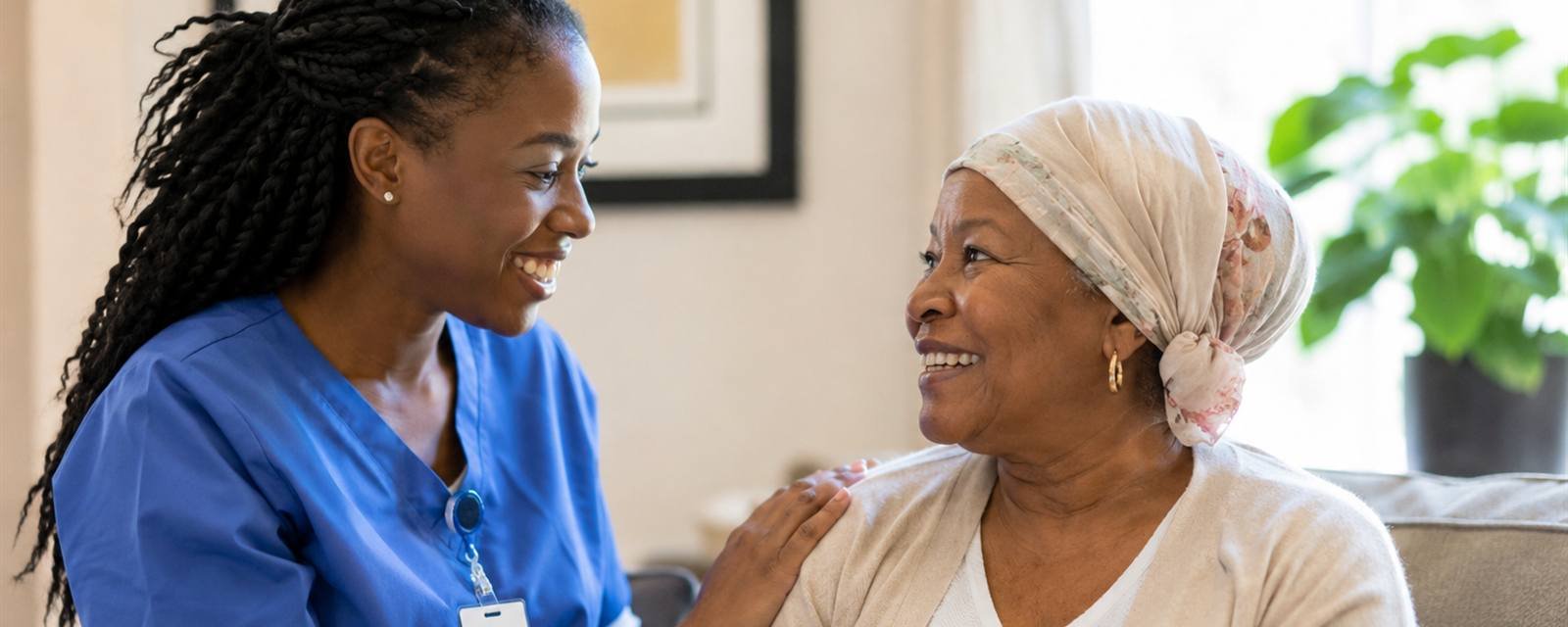 A caregiver and her client sitting together, talking and smiling.
